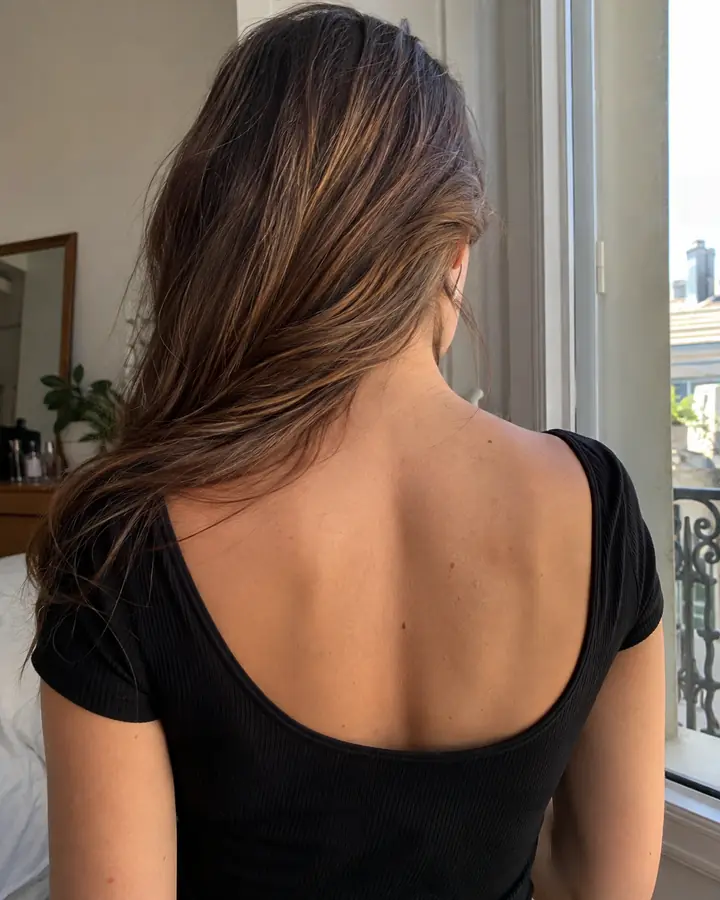 Woman seen from behind with long natural brown hair and a black top